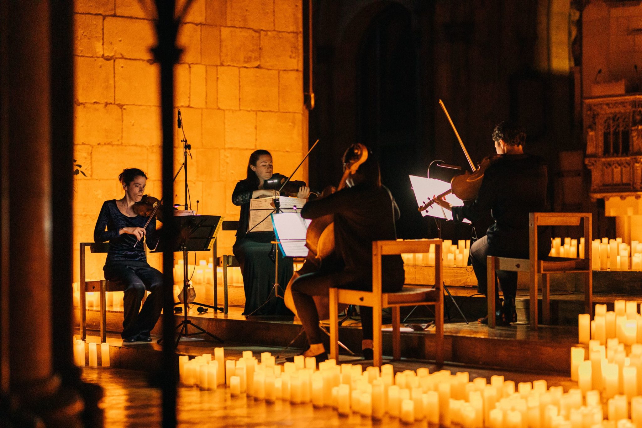 A string quartet performing at a Candlelight concert surrounded by candles.