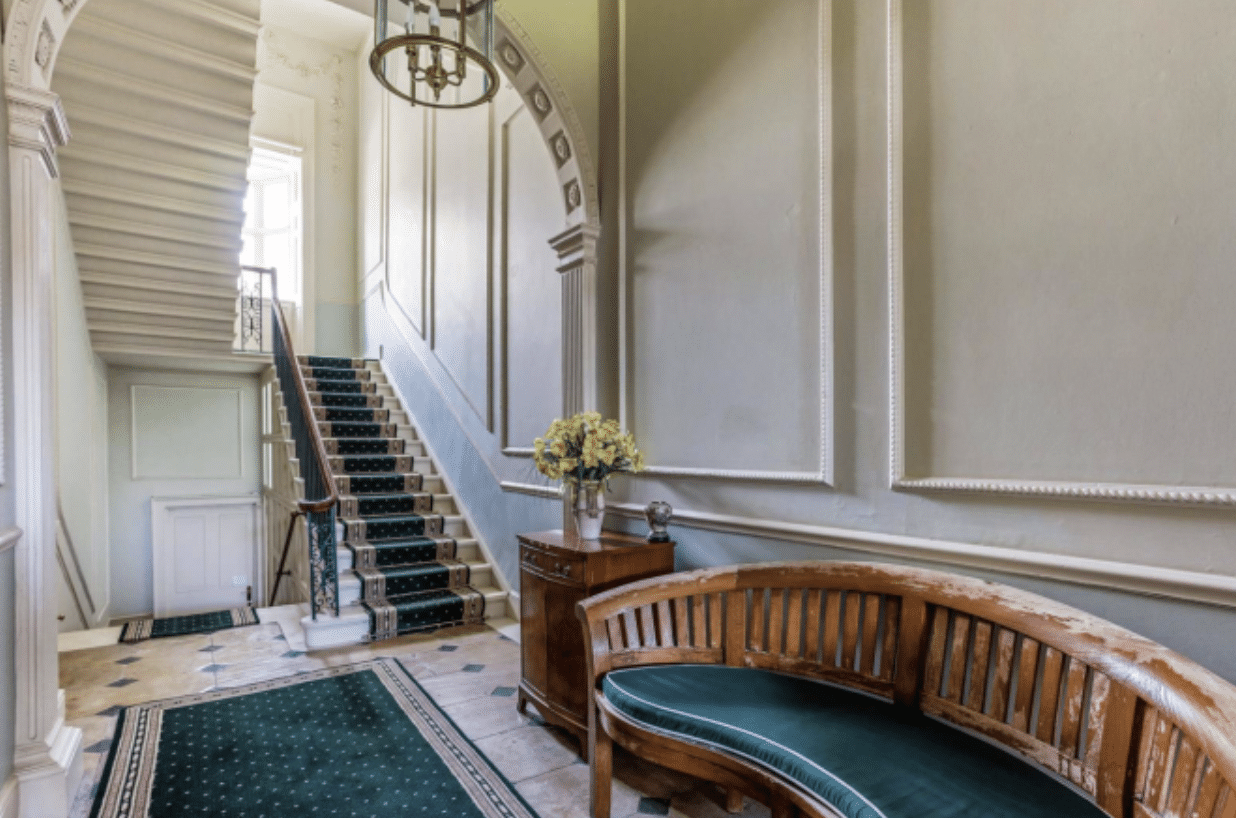 A regal room with a grand staircase and green accents